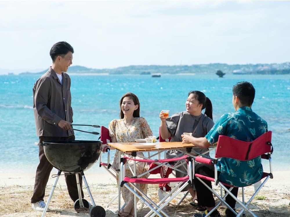Four men and four women are barbecuing at the beach.