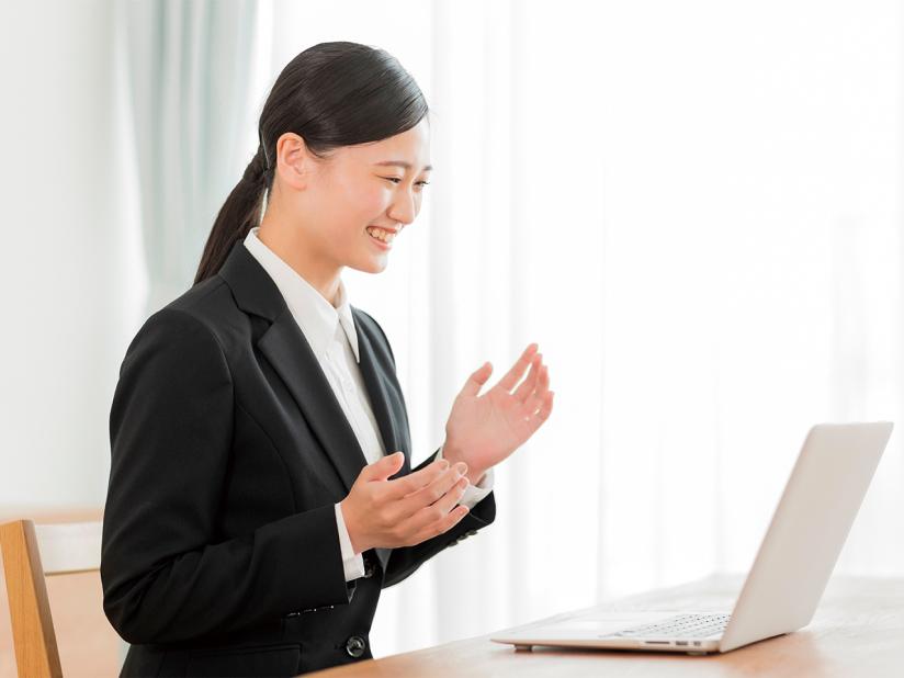 ノートパソコンを用いてオンライン通話で話すスーツを着た女性